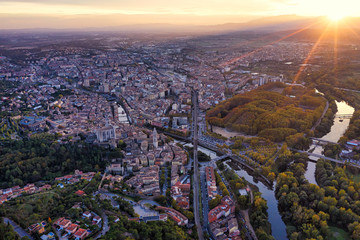 Aerial view of the Spanish city of Girona. Sunset sky, houses, streets, city park and roads. - 306196507