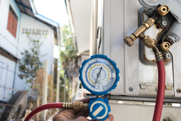 Technicians use manifold gauges to check the refrigerant pressure of air conditioners. - obrazy, fototapety, plakaty