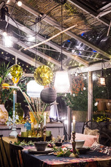 Decorated greenhouse in trendy christmas setting with dinner table, candles and christmas lights.