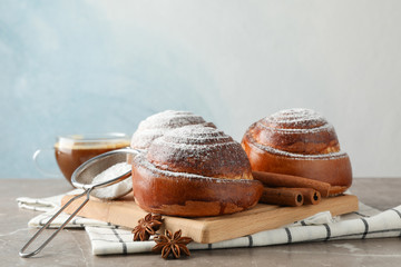 Tasty cinnamon roll with ingredients, coffee on brown table against blue background, space for text. Top view
