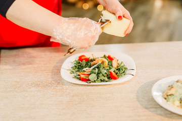 New Year 2020. Christmas table dinner time with salad decorated in New Year style on bokeh background. Christmas beautiful lights on gold warm background. Preparation of Caesar salad.