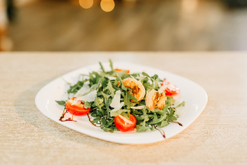 New Year 2020. Christmas table dinner time with salad decorated in New Year style on bokeh background. Christmas beautiful lights on gold warm background.