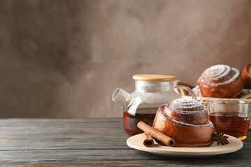 Cinnamon rolls, tea and wicker basket on wooden table, space for text