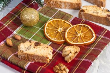 Obraz na płótnie Canvas Traditional Italian Biscotti or Cantuccini cookies with hazelnuts, almonds, walnuts on a red-green napkin with slices of dried oranges. Christmas and New Year's baking.