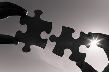 Two hands connecting puzzle piece.