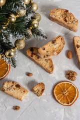 Traditional Italian biscotti or Cantuccini cookies with hazelnuts, almonds, walnuts on a gray background with slices of dried oranges and a Christmas tree. The concept of Christmas baking