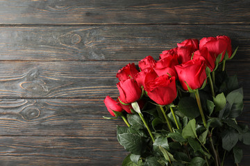 Fototapeta na wymiar Bouquet red roses on wooden background, space for text