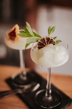 Two gin based sorbet cocktails on a black slate with tea spoon. Concept of refreshing cocktails and alcoholic drinks. Selective focus on the glasses.