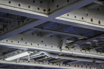 Construction pipes and girders made from industrial grade iron steel pained white roof of a garage area sturdy and solid. Heavy duty building taking a lot of weight in a large boat commercial.