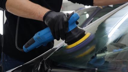 The man polishes the cars from body scratches, car service, autoshop, washing, polishing.