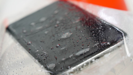 Hand laying scratch protective film on a smartphone closeup phone be waterproof shot on white...