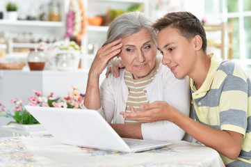 Portrait of grandmother with her grandson using laptop at home