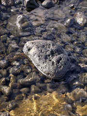 rundgeschliffener lavastein von meerwasser umspült