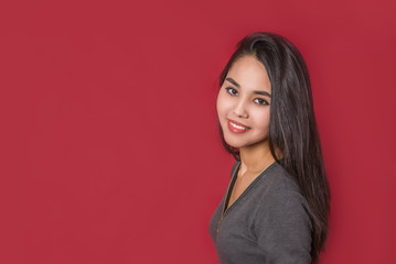 Obraz premium young attractive girl with long black hair on red background in Studio. the girl on the casting. classic portrait copy space