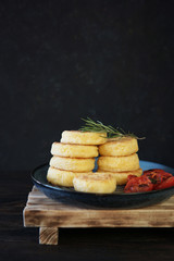  Fried corn polenta with grilled cherry tomatoes and rosemary on rustic table. Copy space. Traditional Italian or Brazilian food. Dark background, selective focus.         