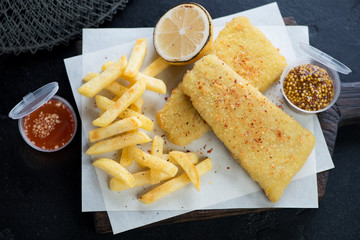 Fish and chips or breaded fish fillet with french fries, close-up, studio shot