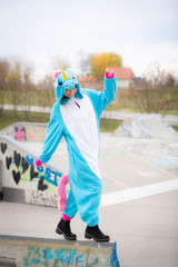 beautiful young woman wearing turquoise unicorn onesie in urban environment