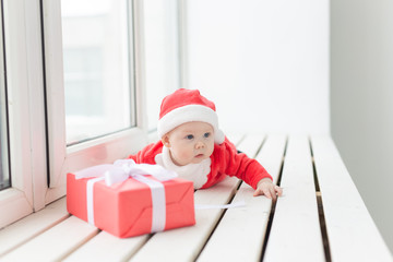 Beautiful little baby celebrates Christmas. New Year's holidays. Baby in a Christmas costume and in santa hat