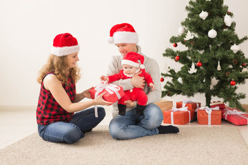 Happy couple with baby celebrating Christmas together at home.