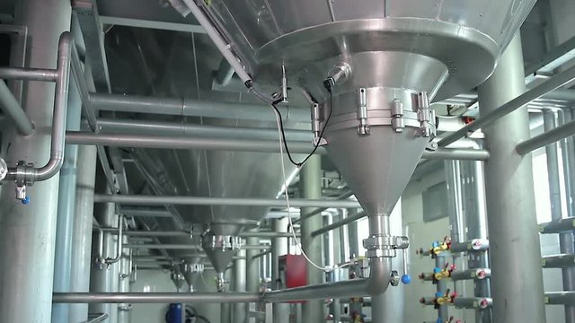 Industrial zone, Steel pipelines, valves, cables and walkways. Steel tanks in interior of a modern factory. Modern Craft Brewery. Steel fermentation vessels. Pressure gauge, measuring instrument.