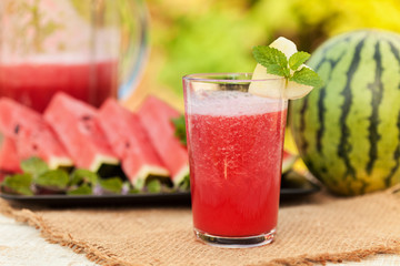 Summer refreshment - watermelon smoothie with fruit slices and whole melon in background