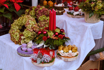 Various Christmas wreaths and centre table of flowers and candles for sale on a Market table