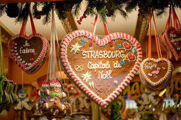 Gingerbread cookies in shape of hearts hanging from stall with messages of Christmas, Love and Strasbourg and a gingerbread man at the Strasbourg Christmas Market - obrazy, fototapety, plakaty