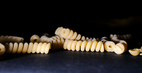 Naklejka premium Dried pasta on the dark table, with copy space.