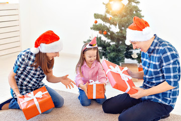 Obraz premium Holidays and presents concept - Portrait of a happy family opening gifts at Christmas time