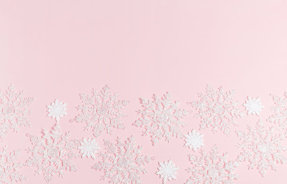 Christmas composition. Frame made of balls and snowflakes on pastel pink background.