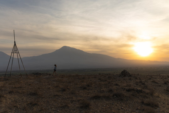 Beautiful and slender Girl travels in Armenia, Yerevan. At sunset, she jump silhouettes against the backdrop of Mount Ararat. Very beautiful landscape