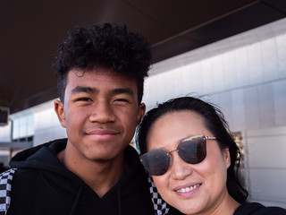 Asian mother with African American mixed race teenage son at airport.