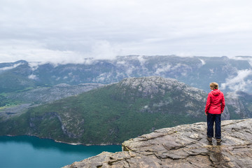 Fototapeta na wymiar Girl on Prekestolen or Pulpit Rock in the rain. Norway.
