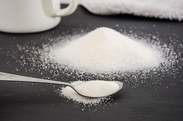 white sugar and spoon on a black background