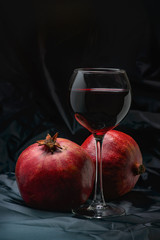 Glass of red wine with large ripe pomegranates