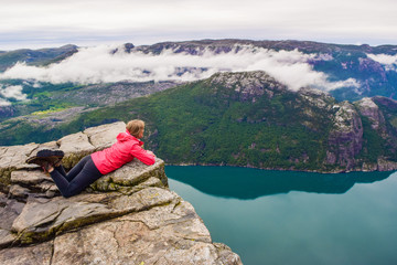 Naklejka premium Girl on Prekestolen or Pulpit Rock in the rain. Norway.