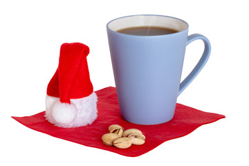 Obraz na płótnie Canvas Coffee cup background isolated. Close-up of a blue coffee mug and pistachios with a Santa hat on a red napkin isolated on a white background. Concept morning coffee in christmas time. Macro.