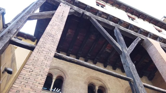 Perspective bottom view of medieval architecture of an historic building with wooden balcony. In the historic downtown of Bologna city, Italy.