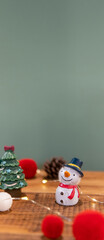 Fototapeta premium Christmas decoration (snowman, santa, gift box, pine cones, socks, lights) on green background