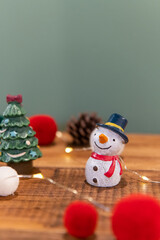 Christmas decoration (snowman, santa, gift box, pine cones, socks, lights) on green background