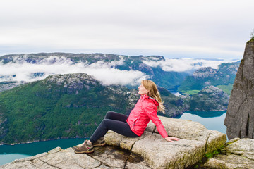 Naklejka premium Girl on Prekestolen or Pulpit Rock in the rain. Norway.