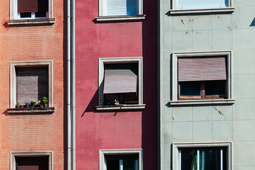 Cute windows with wooden shutters on the facade of modern residential building made of red and orange bricks. Lovely street view in Barcelona, Spain. Travel concept