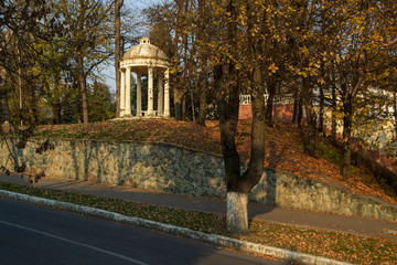The rotunda of the bright stone. Round dome and columns. Autumn park.