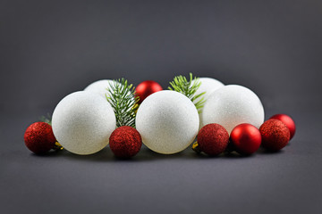 Pile of traditional white and red Christmas tree ornaments baubles and pine branches on dark background