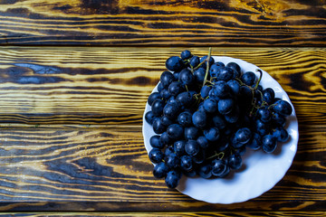branch of black grapes on a wooden table, top view