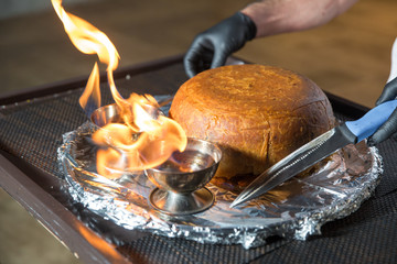 Traditional oriental dish on tableware Azerbaijan with fire on a table in restaurant .the chef cuts off the drill. Shah pilaf. Khan pilaf in a pita.