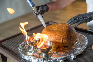 Traditional oriental dish on tableware Azerbaijan with fire on a table in restaurant .the chef cuts off the drill. Shah pilaf. Khan pilaf in a pita.