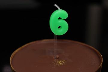 6の形をしたろうそくを立てたチョコレートケーキ