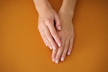 Hands of a young woman with beautiful manicure on a beige background. Female manicure. Close-up.