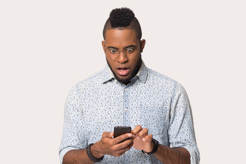 Amazed African American man looking at phone with open mouth